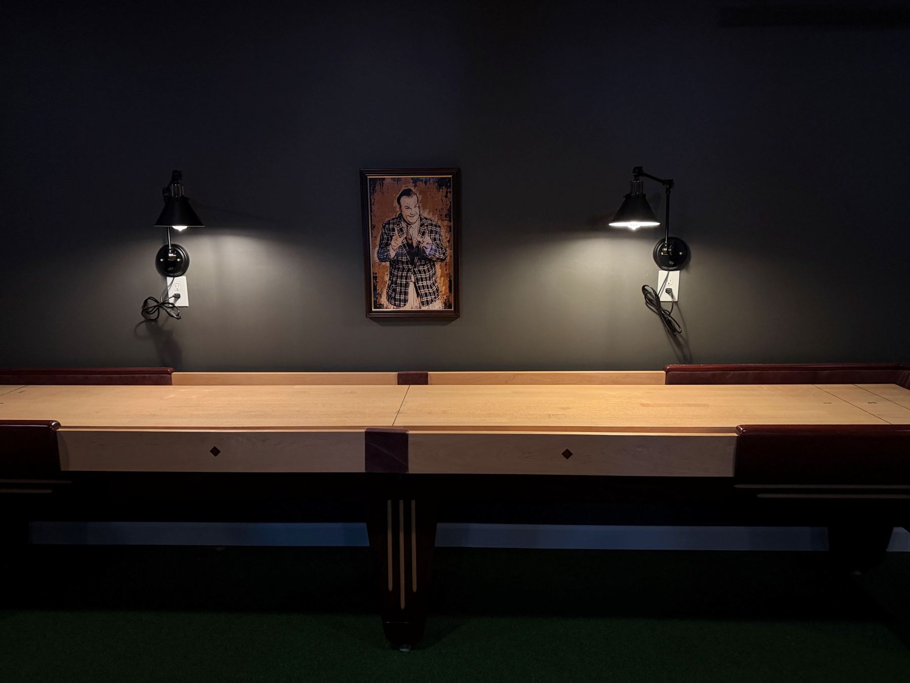 Clubhouse wall with sconces and framed art above the shuffleboard table