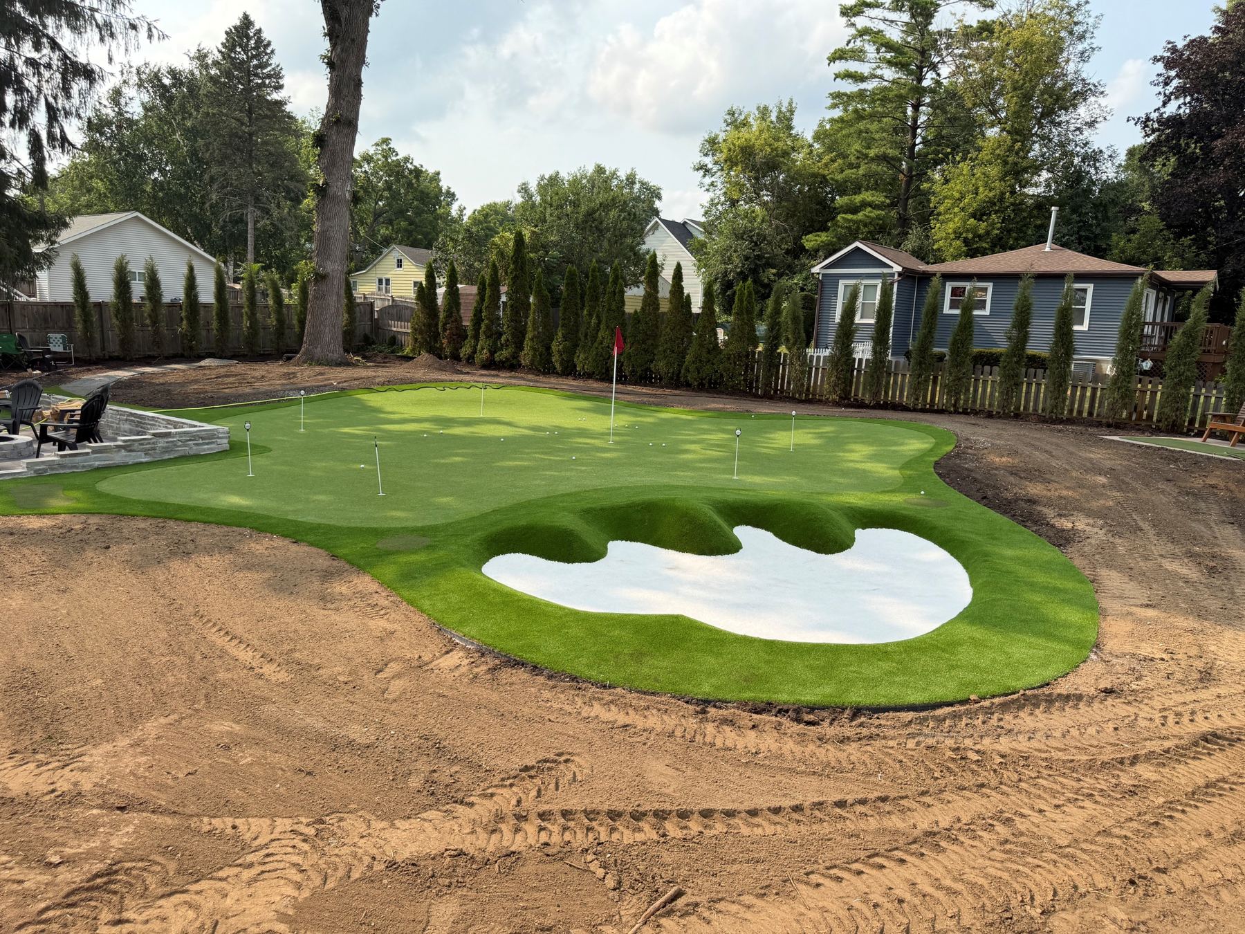 Putting green with a sculpted bunker and multiple cups and flags